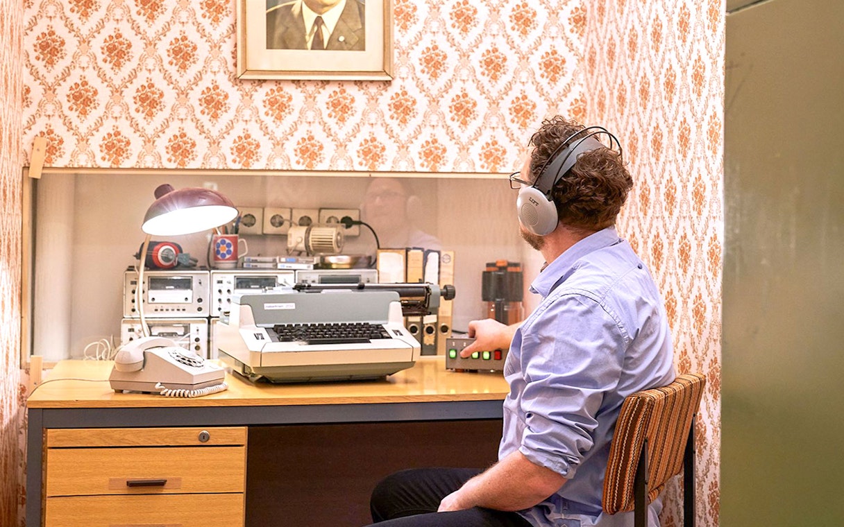 Man using vintage typewriter and equipment at DDR Museum Berlin.
