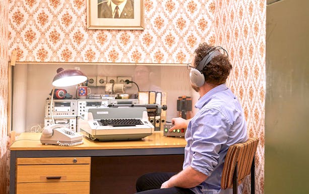 Man using vintage typewriter and equipment at DDR Museum Berlin.