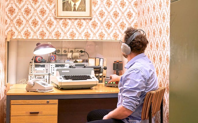 Man using vintage typewriter and equipment at DDR Museum Berlin.