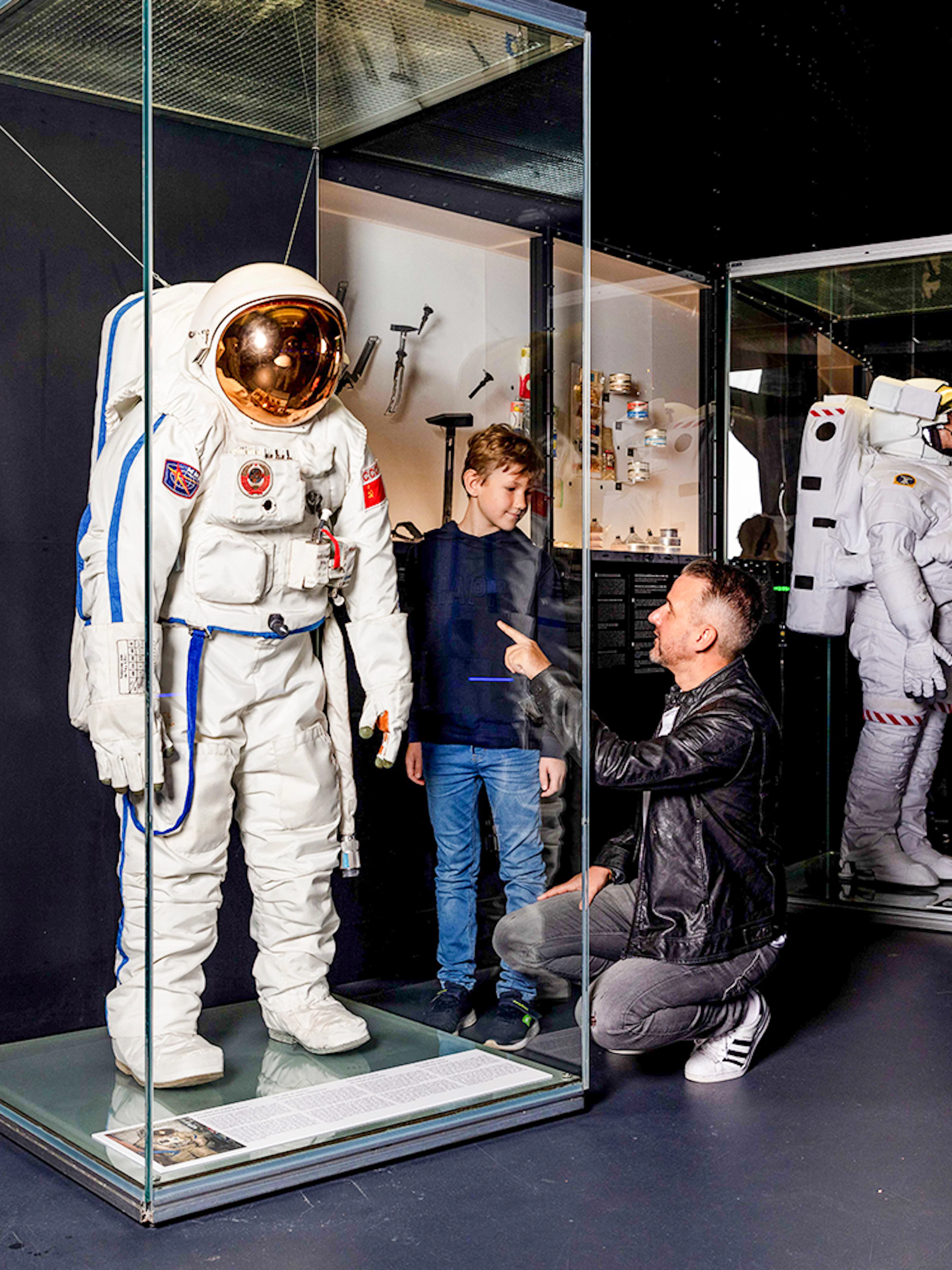 Astronaut suit display at Swiss Museum of Transport with visitors observing.