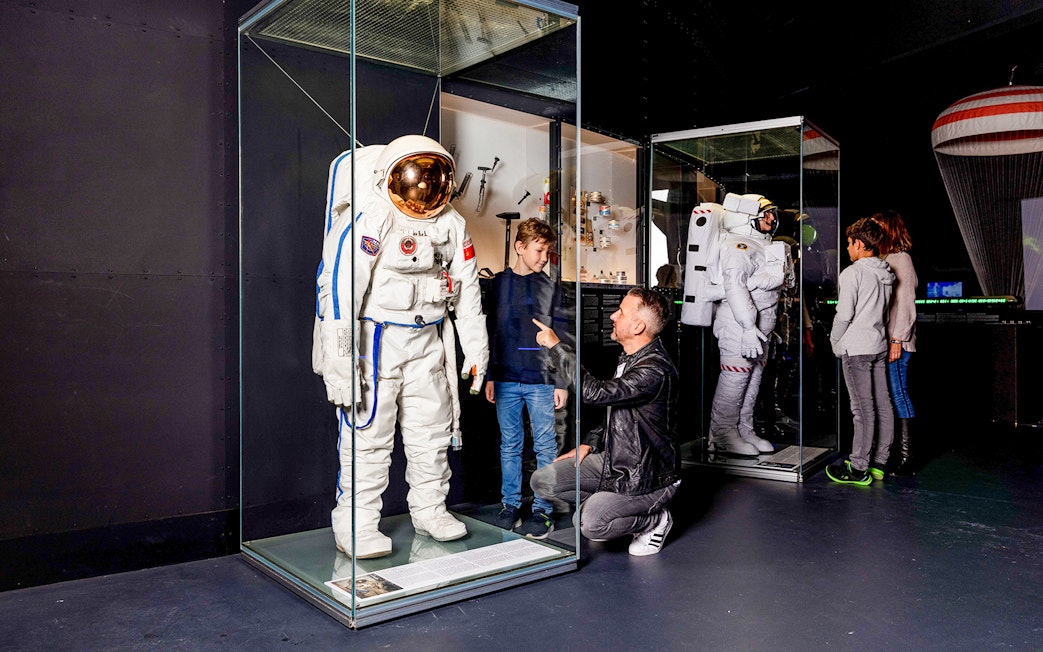 Astronaut suit display at Swiss Museum of Transport with visitors observing.
