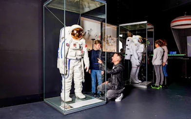 Astronaut suit display at Swiss Museum of Transport with visitors observing.