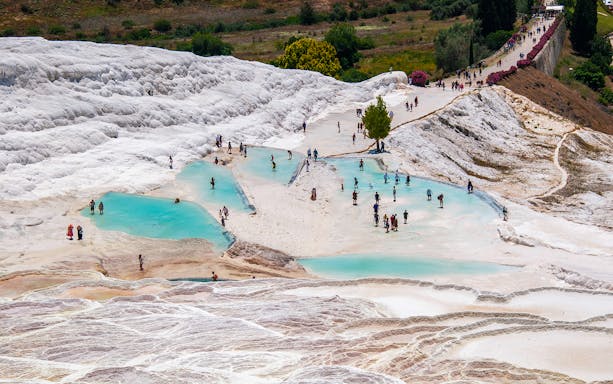 Tourists exploring Pamukkale's travertine terraces in Antalya, Turkey.