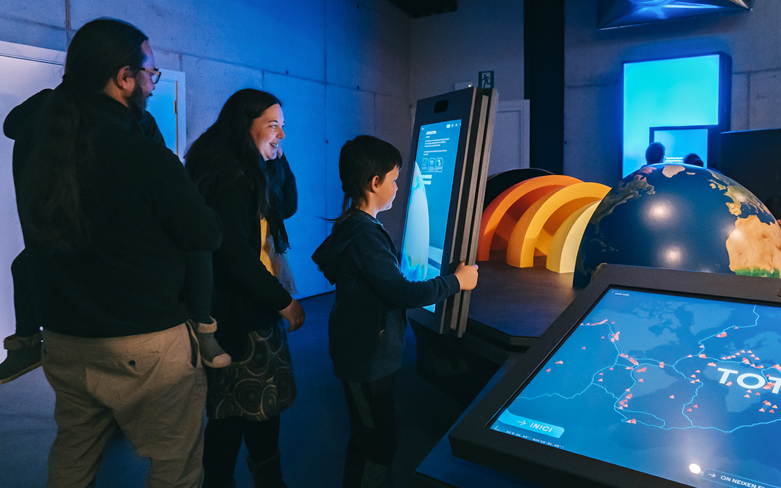 Visitors interacting with digital displays at Espai Crater exhibit.