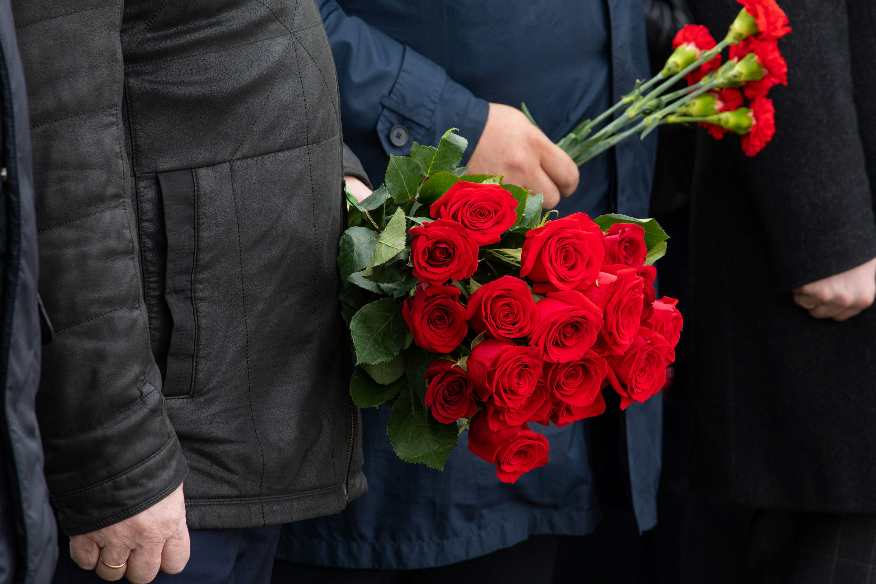 People holding red roses at 9/11 Memorial Glade ceremony.