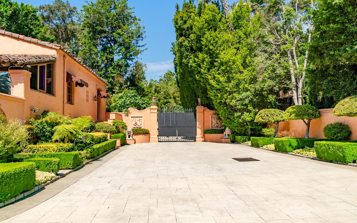Beverly Hills mansion entrance with manicured hedges and iron gate, known as "The Godfather House.