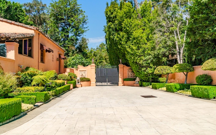 Beverly Hills mansion entrance with manicured hedges and iron gate, known as "The Godfather House.