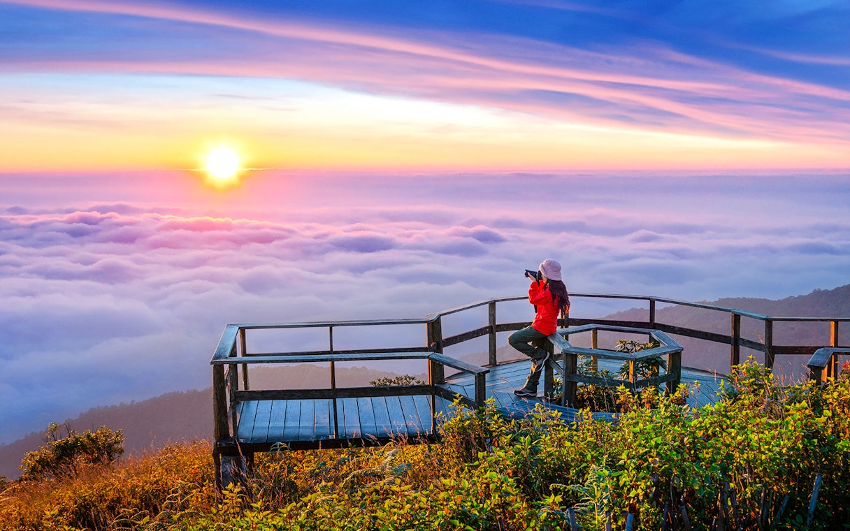 Tourist photographing sunset at Kew Mae Pan viewpoint, Doi Inthanon, Chiang Mai, Thailand.
