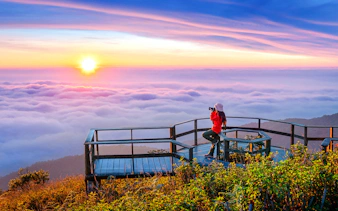 Tourist photographing sunset at Kew Mae Pan viewpoint, Doi Inthanon, Chiang Mai, Thailand.