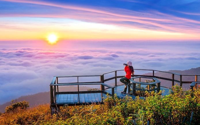 Tourist photographing sunset at Kew Mae Pan viewpoint, Doi Inthanon, Chiang Mai, Thailand.