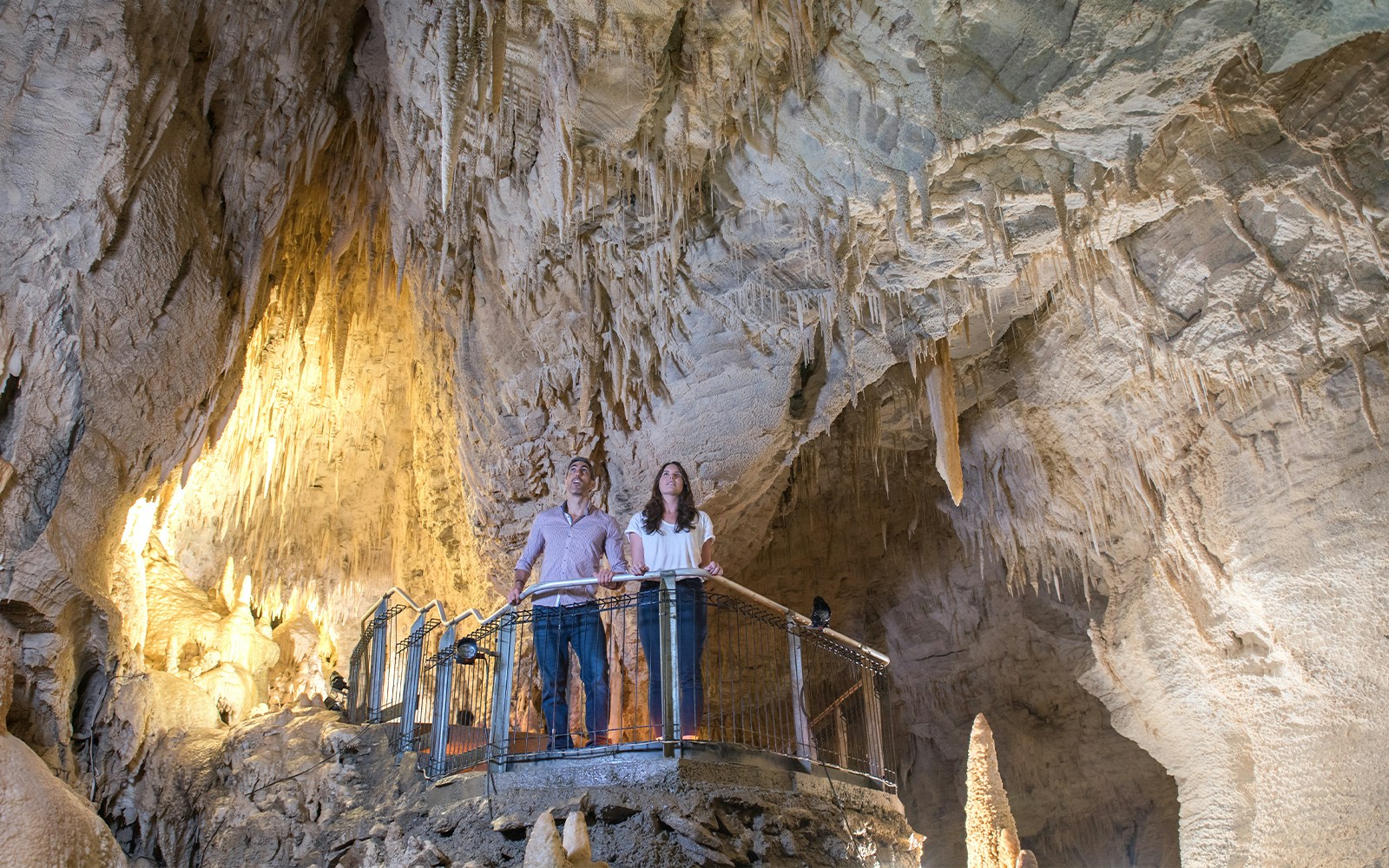 Visitors exploring stalactites in Ruakuri Cave, New Zealand.