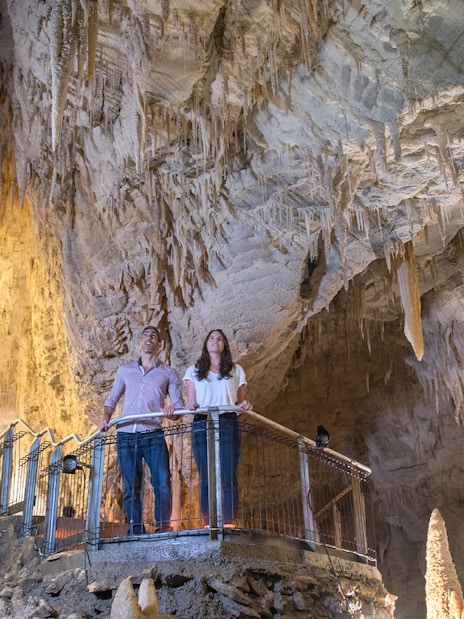 Visitors exploring stalactites in Ruakuri Cave, New Zealand.
