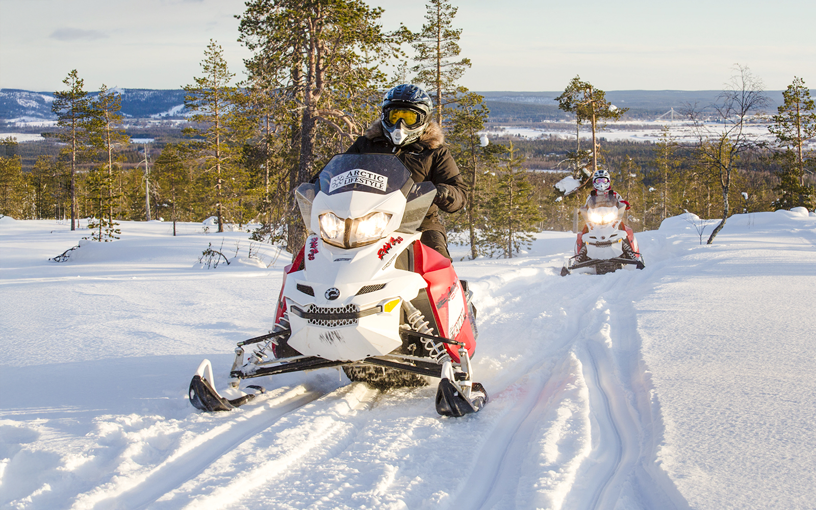 Snowmobiles racing through snowy forest in Rovaniemi, Finland.