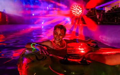 Child enjoying a glowing tube ride at AquaGlow, Adventure Island Tampa.