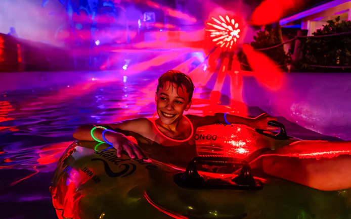 Child enjoying a glowing tube ride at AquaGlow, Adventure Island Tampa.