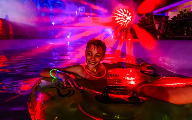 Child enjoying a glowing tube ride at AquaGlow, Adventure Island Tampa.