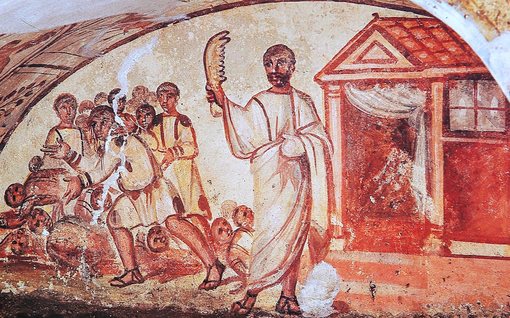 Ancient fresco depicting figures in Roman attire inside catacombs on the Appian Way, Rome.