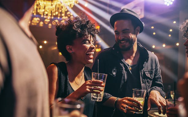 People enjoying drinks and laughing at a lively pub crawl party.