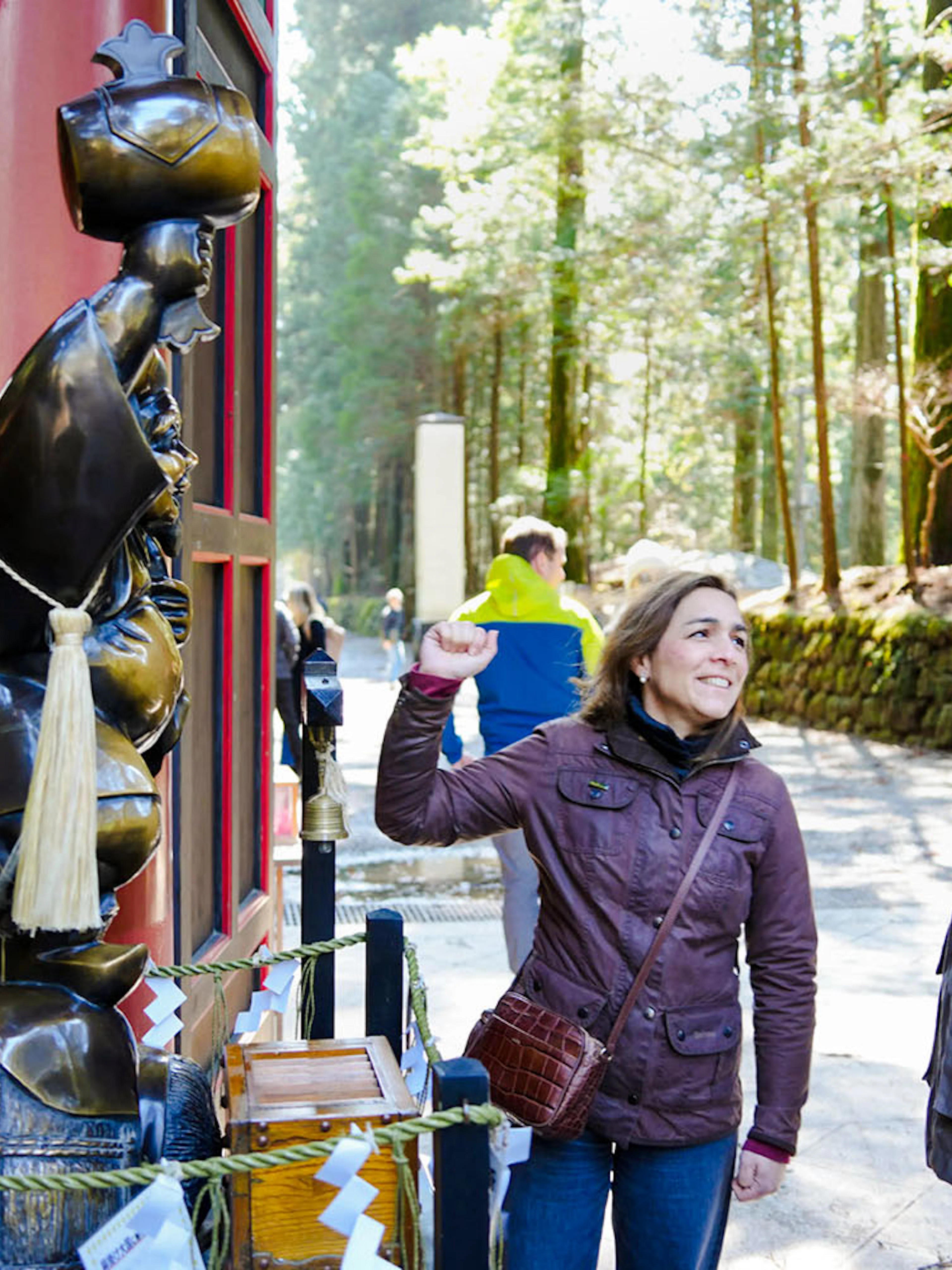 Tourists interacting with a statue at Futarasan Shrine, Nikko.