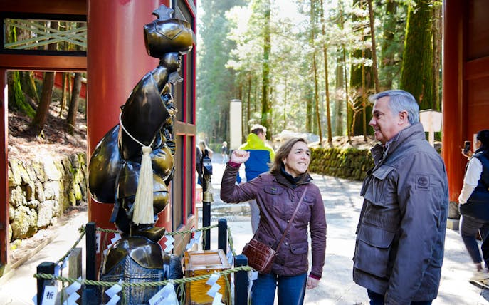 Tourists interacting with a statue at Futarasan Shrine, Nikko.