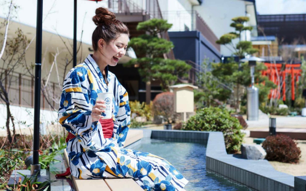 Person in yukata enjoying foot bath at Solaniwa Onsen, Japan.