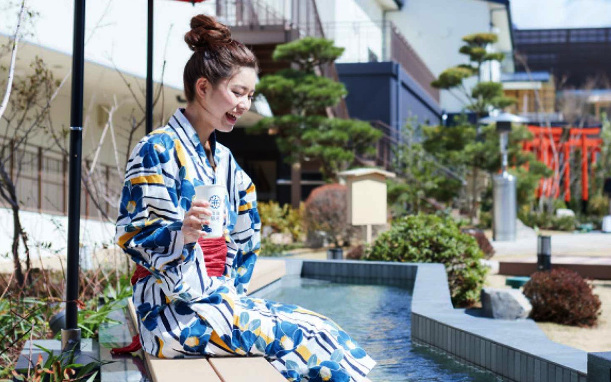 Person in yukata enjoying foot bath at Solaniwa Onsen, Japan.
