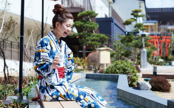 Person in yukata enjoying foot bath at Solaniwa Onsen, Japan.