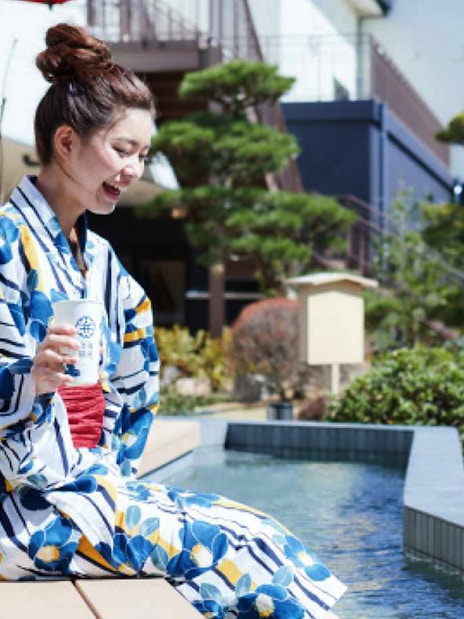 Person in yukata enjoying foot bath at Solaniwa Onsen, Japan.