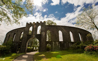 McCaig's Tower in Oban, Scotland, with stone arches and surrounding greenery.