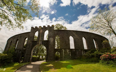 McCaig's Tower in Oban, Scotland, with stone arches and surrounding greenery.