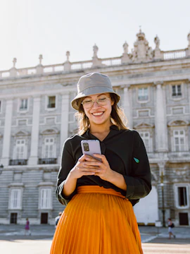Girl using phone in front of Royal Palace of Madrid.