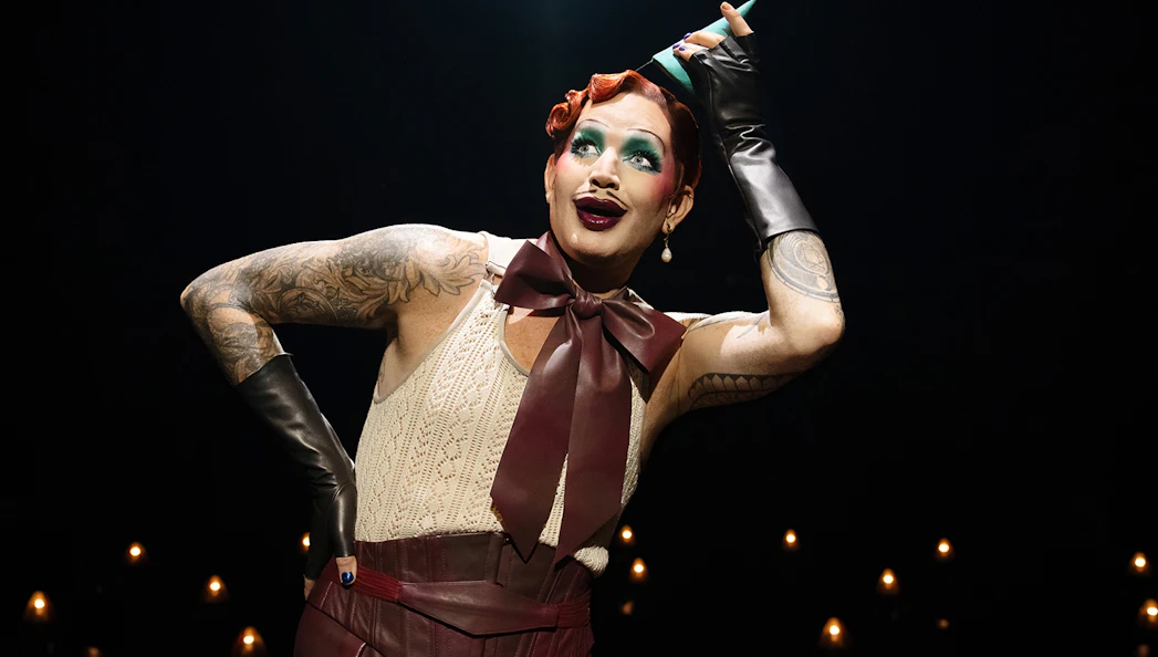 Performer in cabaret show with dramatic makeup and costume.