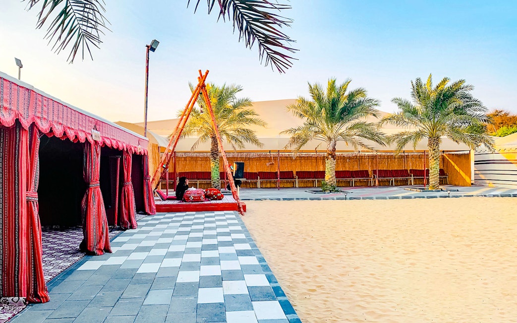 Desert camp site with traditional tents and palm trees in Abu Dhabi.