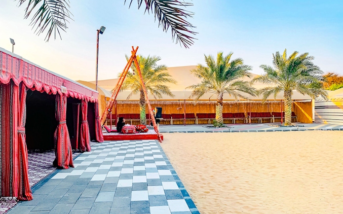 Desert camp site with traditional tents and palm trees in Abu Dhabi.