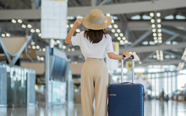 Tourist with suitcase walking inside Bangkok Suvarnabhumi Airport.