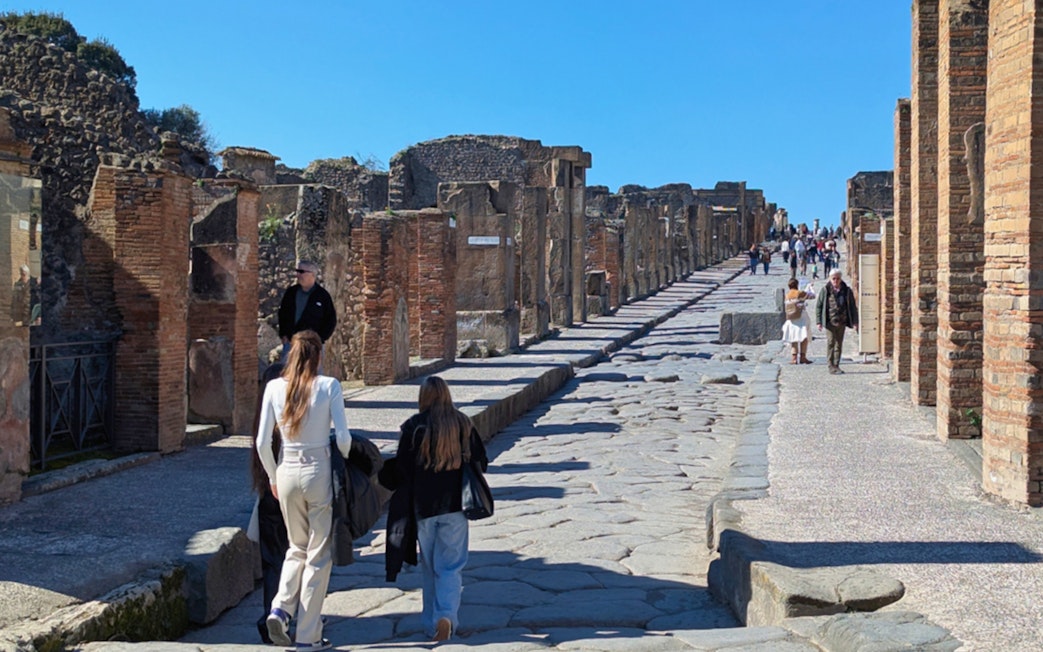 Visitors walking along the ancient cobblestone streets of Pompeii, Italy.