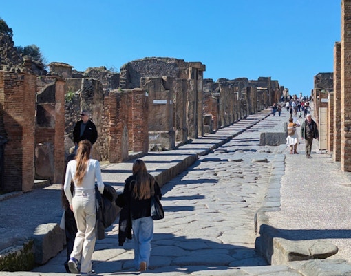 Ancient ruins and cobblestone streets of Pompeii with Mount Vesuvius in the background.