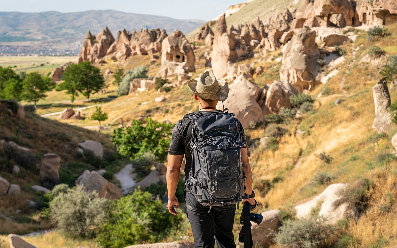Photographer with camera at Zelve Open Air Museum, Cappadocia, overlooking rock formations.