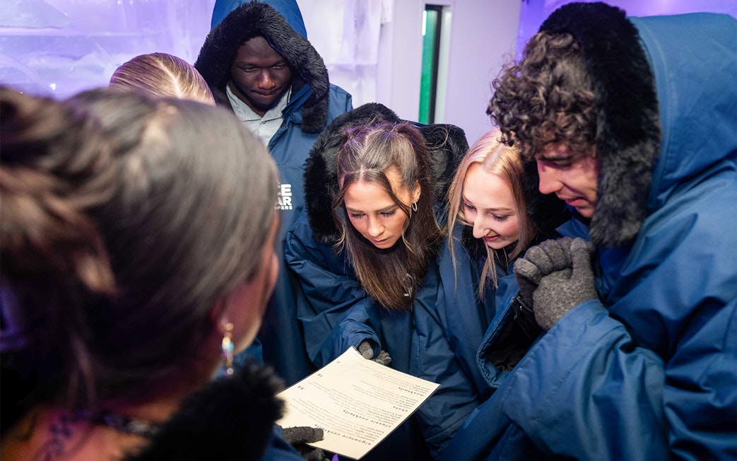 Group in winter coats reading a menu at IceBar Surfers Paradise.
