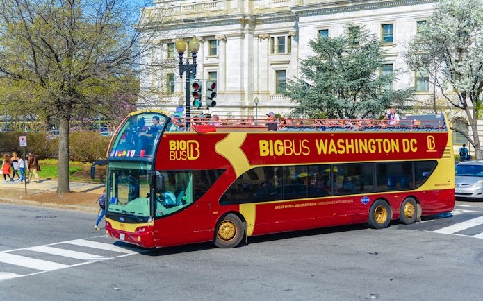Open-top Big Bus tour in Washington DC passing a historic building.