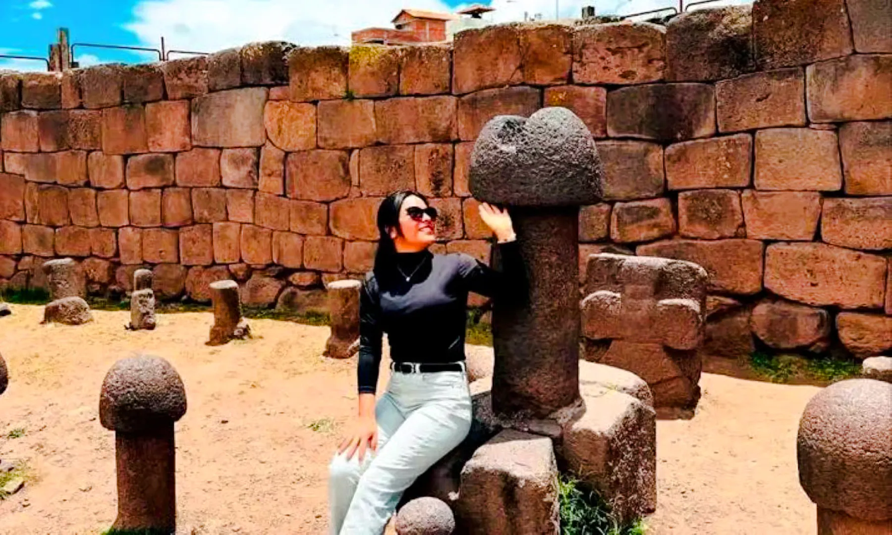 Person sitting by stone sculptures at Chucuito, Puno on Aymara Route tour.