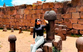 Person sitting by stone sculptures at Chucuito, Puno on Aymara Route tour.