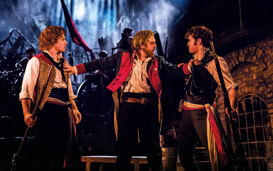 Actors in a dramatic scene from Les Miserables on stage.