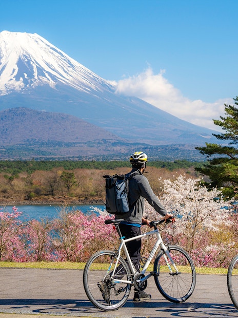 Couple cycling by Lake Yamanaka with Mount Fuji in the background, Japan.