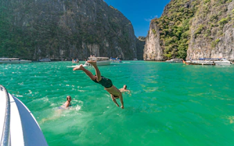 Man diving into turquoise water near cliffs on Phi Phi Islands tour, Phuket.