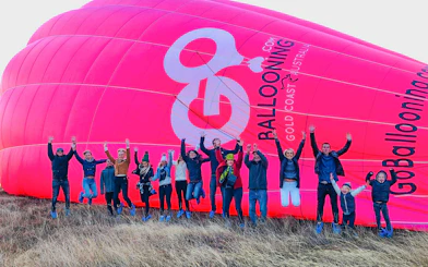 Group jumping in front of a pink hot air balloon in Gold Coast, Australia.