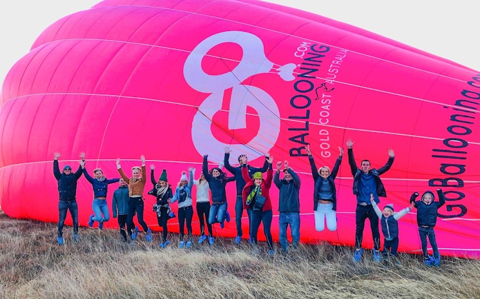 Group jumping in front of a pink hot air balloon in Gold Coast, Australia.