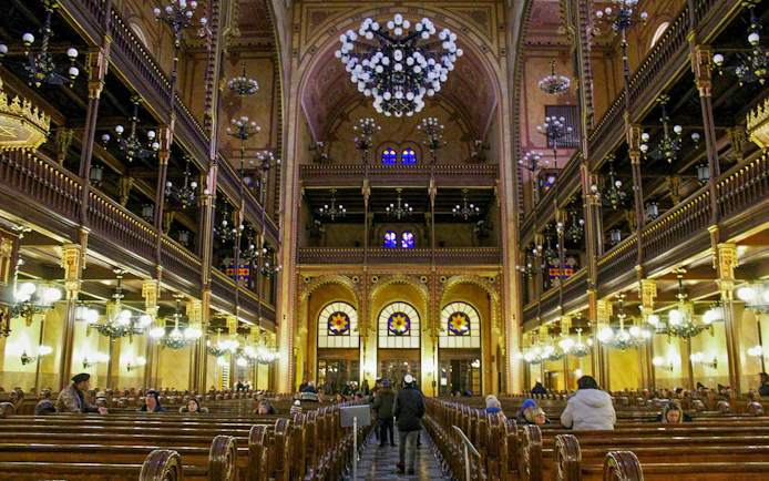 Interior of the Jewish Synagogue in Budapest with ornate chandeliers and stained glass windows.