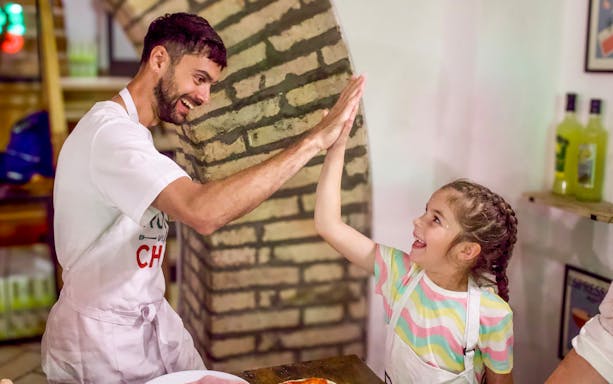 Man and child high-fiving during Rome pizza and tiramisu class.