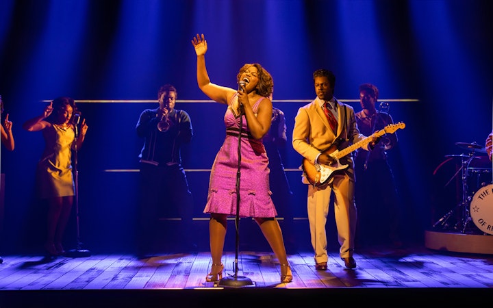 Performer singing on stage with band during TINA – The Tina Turner Musical.